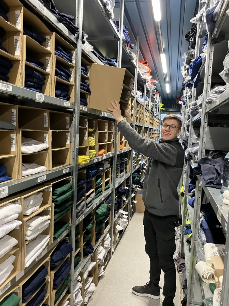 Dualer Student im Lager der bardusch Niederlassung Torun beim Einr&auml;umen von Kleidung w&auml;hrend seiner ersten Dienstreise