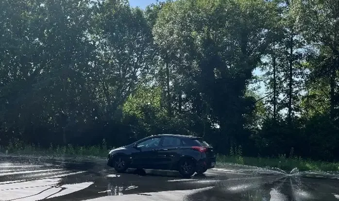 Auto f&auml;hrt &uuml;ber eine nasse Strecke beim Fahrsicherheitstraining, um das richtige Bremsverhalten zu &uuml;ben