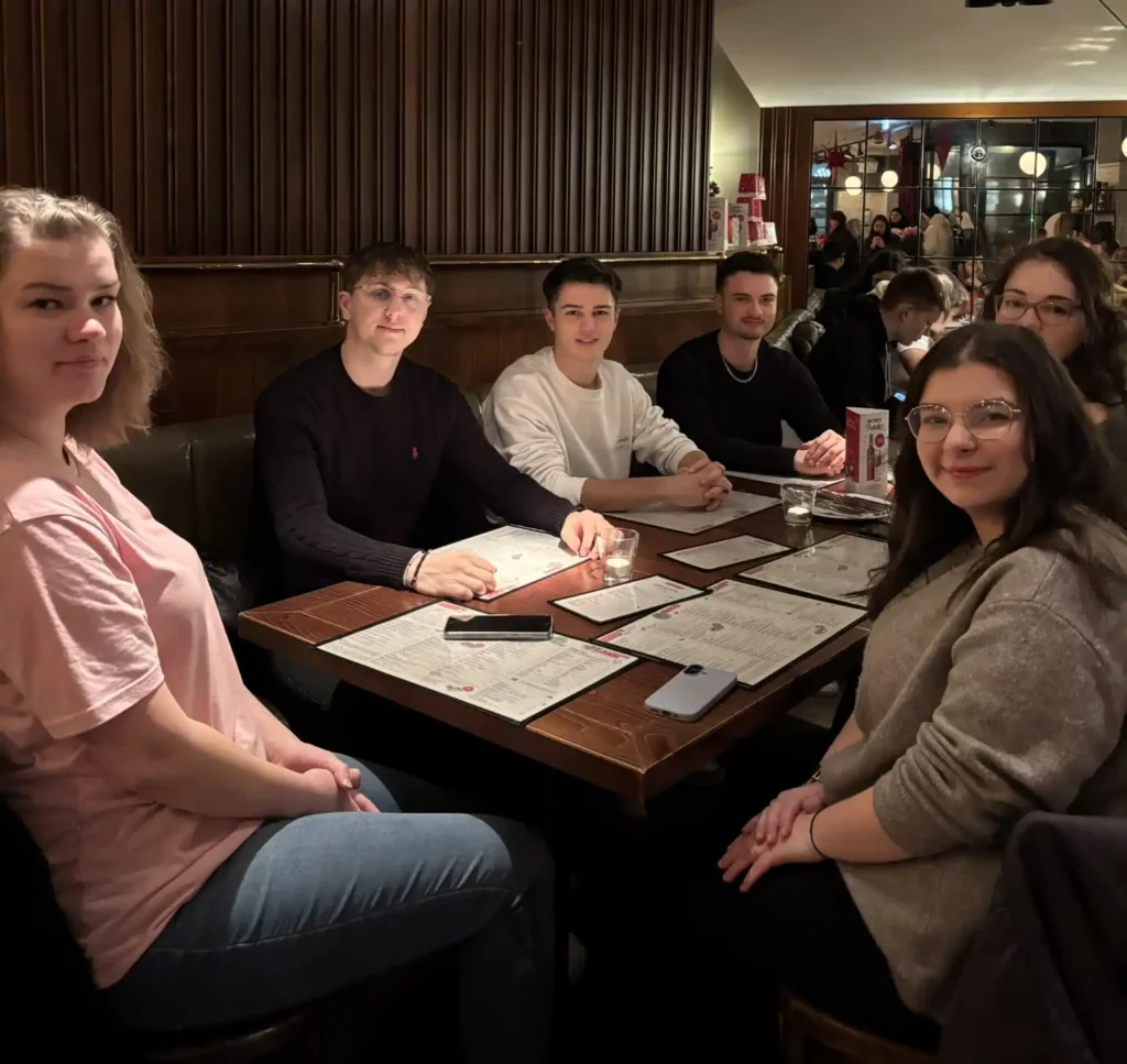 Auszubildende sitzen gemeinsam am Tisch im Restaurant und warten aufs Essen