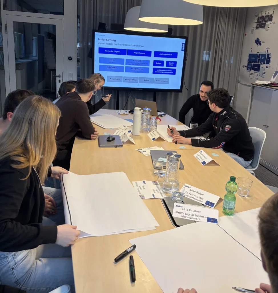 Projektarbeit in der Schulung: Struktur und Planung im Fokus Azubis erarbeiten in einer Projektmanagement-Schulung gemeinsam Projektinhalte und nutzen Vorlagen vor einer Präsentationsfolie zur Projektinitialisierung