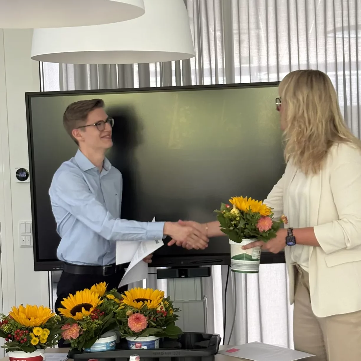 Ein Absolvent erhält bei der Zeugnisübergabe von bardusch persönliche Glückwünsche und einen Blumenstrauß