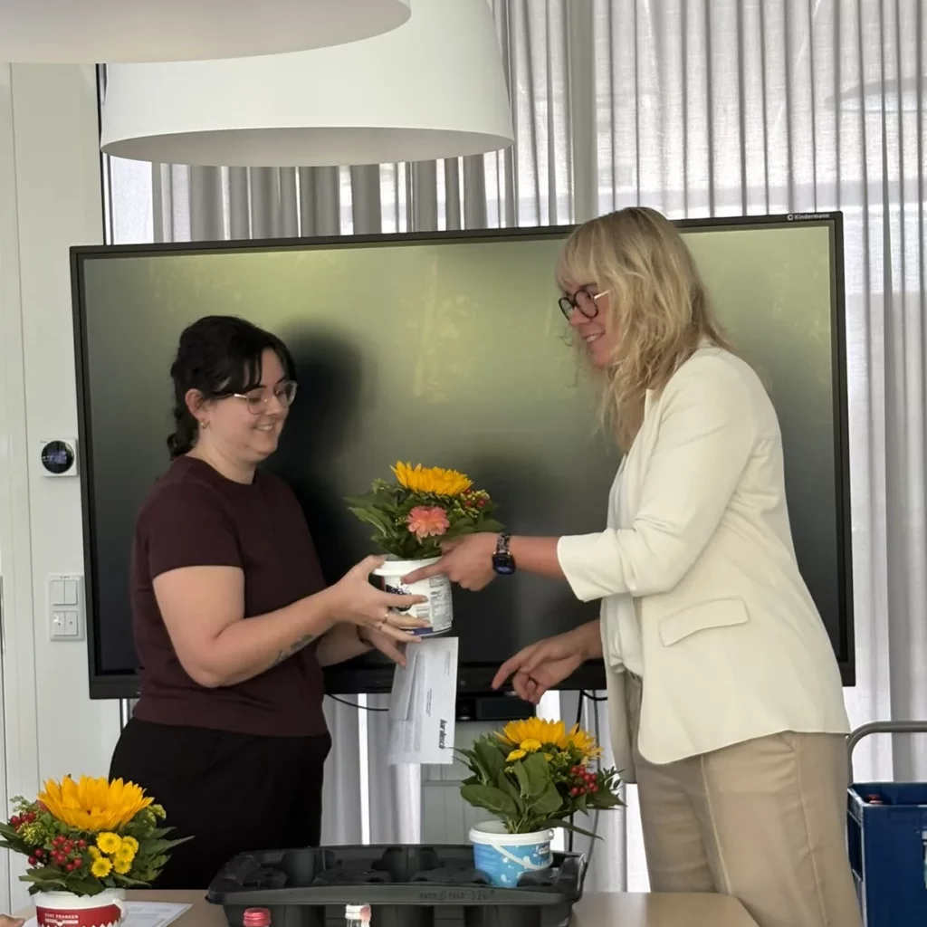Feierliche Übergabe eines Blumenstraußes an eine Absolventin zum erfolgreichen Ausbildungsabschluss bei bardusch